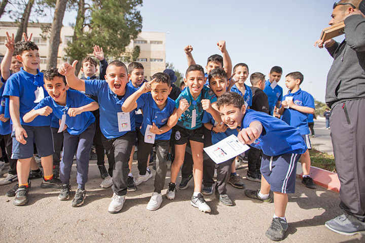Grundschulkinder von Talitha Kumi - etwa 20 Jungen mit blauen Shirts - stehen gespannt am Start zu einem Spendenlauf. Sie gestikulieren wild in die Kamera.